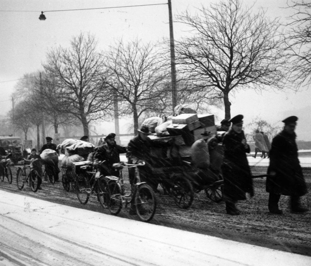 二战后，欧洲境内的德国难民冒着暴风雪走过汉堡街头，身后拖着他们成堆的个人物品。图片：Photo byKeystone/Getty Images